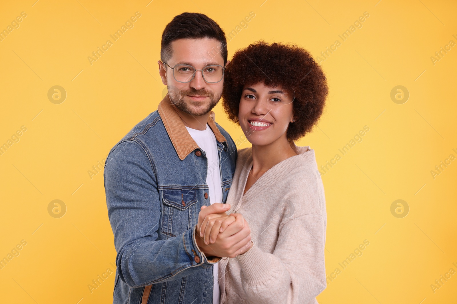 Photo of International dating. Lovely couple dancing on orange background