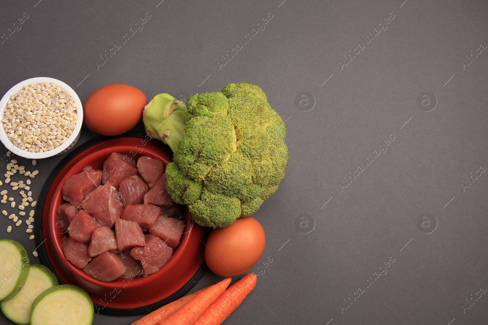 Photo of Raw meat in bowl and healthy products for pet on black background, flat lay. Space for text