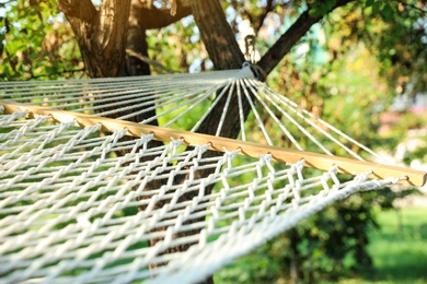 Photo of Comfortable net hammock hanging in green garden, closeup