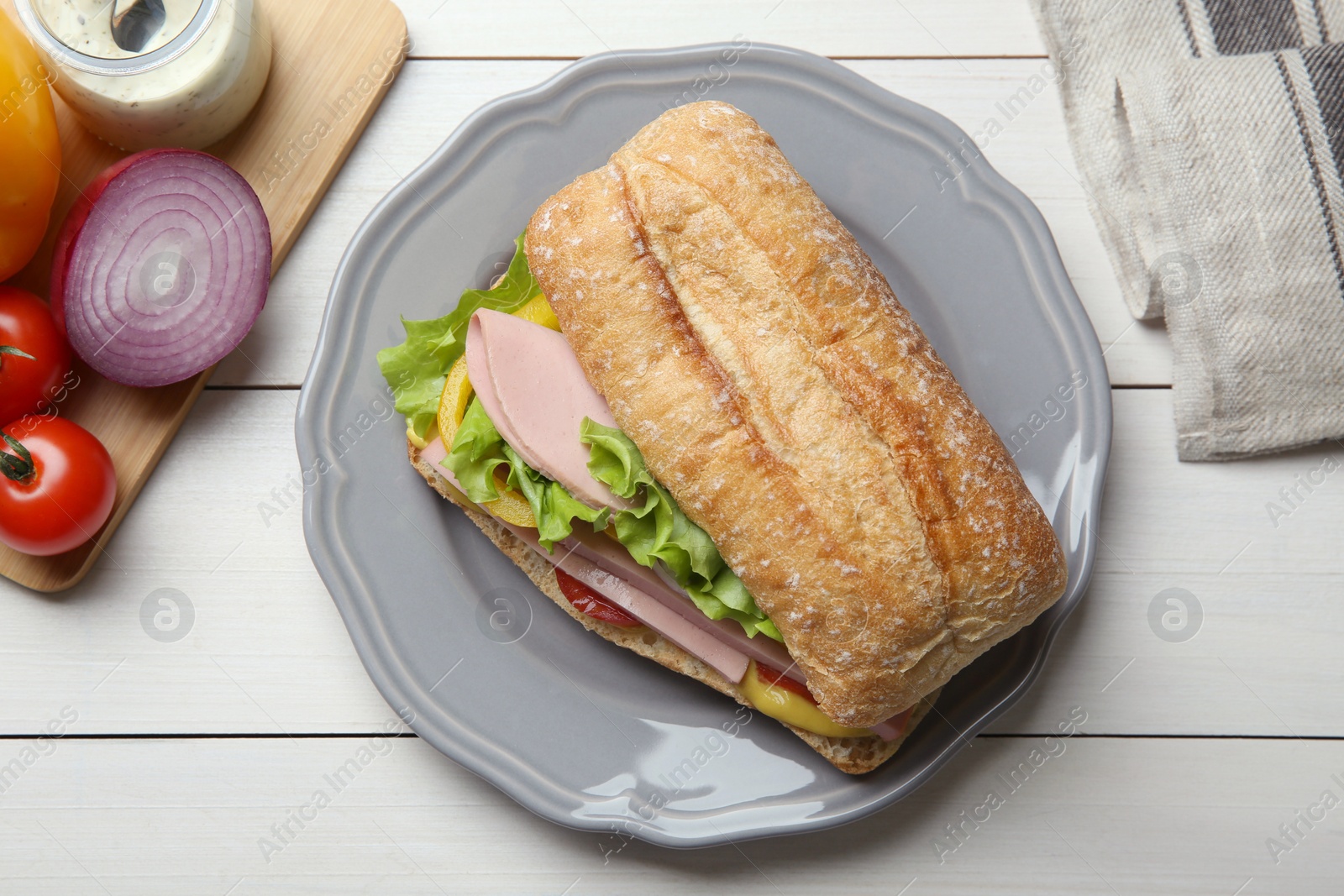Photo of Tasty sandwich with boiled sausage, cheese and vegetables on white wooden table, flat lay