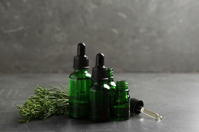 Composition with bottles of conifer essential oil on grey table