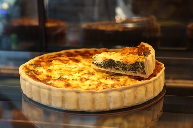 Photo of Delicious cheese quiche on counter in bakery shop, closeup