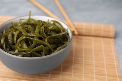 Photo of Tasty seaweed salad in bowl served on gray table, closeup