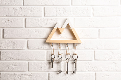 Wooden key holder on white brick wall indoors