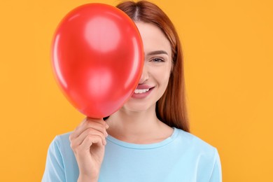Photo of Happy woman with red balloon on orange background