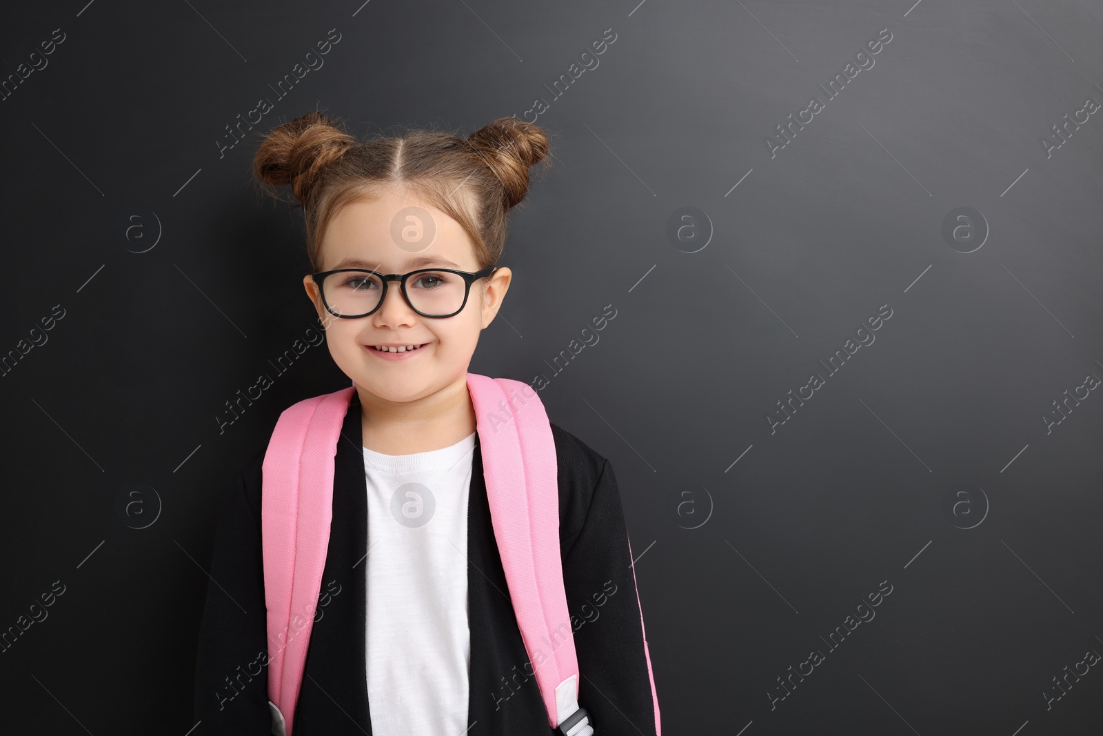 Photo of Happy little school child with backpack near chalkboard. Space for text