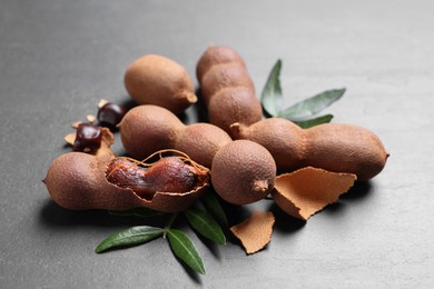 Photo of Delicious ripe tamarinds and leaves on black table