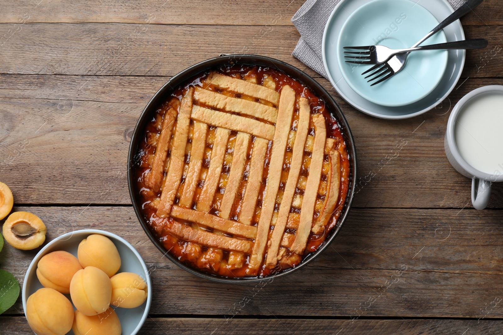 Photo of Delicious apricot pie in baking dish and fresh fruits on wooden table, flat lay