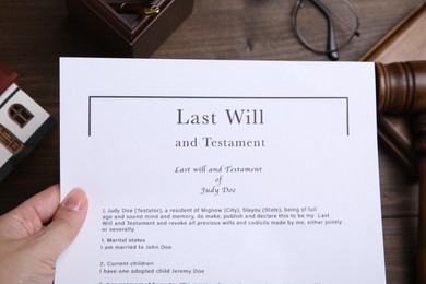 Woman holding last will and testament at table, top view