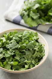 Photo of Cut fresh green cilantro in bowl on light grey marble table, closeup