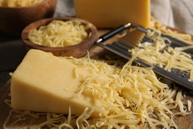 Photo of Grated and whole piece of cheese on table, closeup