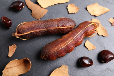 Peeled tamarind pods and seeds on black table, flat lay