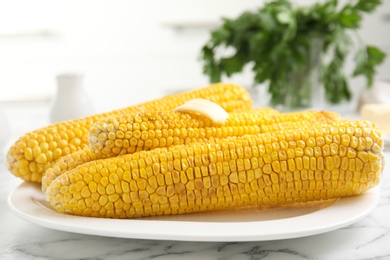 Photo of Fresh grilled corn cobs with butter on white marble table, closeup