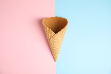 Photo of Empty wafer ice cream cone on color background, top view