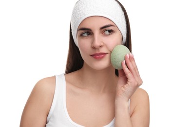 Photo of Young woman with headband washing her face using sponge on white background