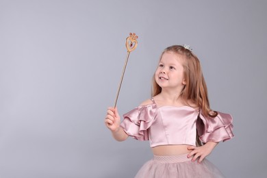 Photo of Cute girl in fairy dress with small crown and magic wand on light grey background, space for text. Little princess
