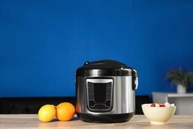 Photo of Modern multi cooker and ingredients on table in kitchen