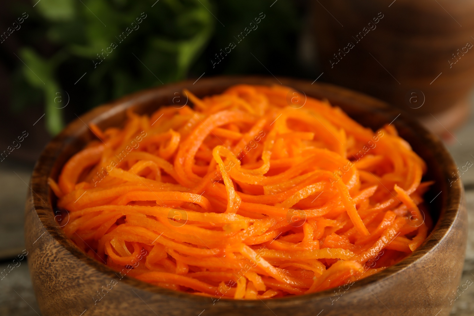 Photo of Delicious Korean carrot salad in wooden bowl, closeup