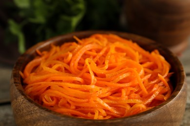 Photo of Delicious Korean carrot salad in wooden bowl, closeup