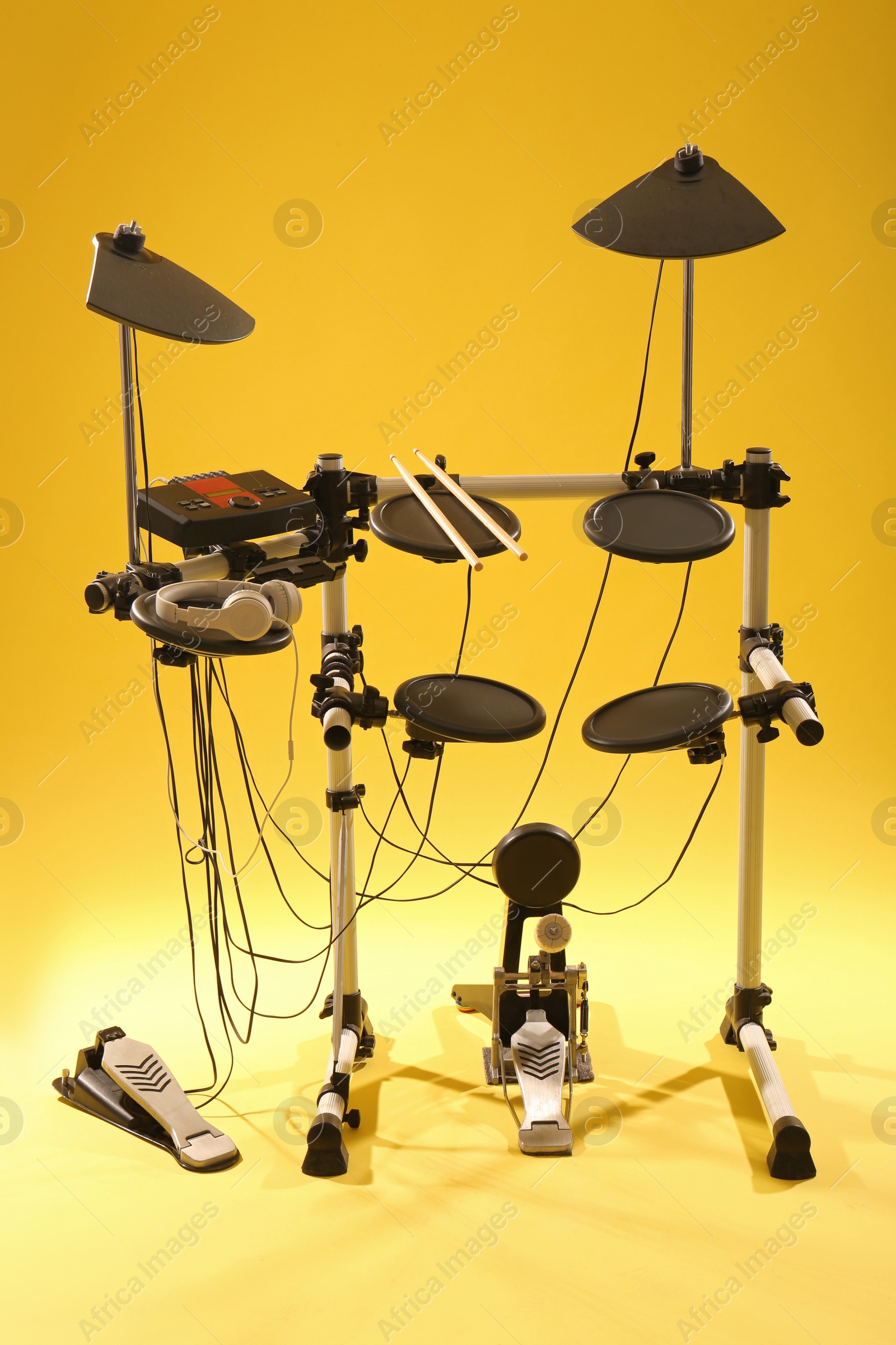 Photo of Modern electronic drum kit on yellow background. Musical instrument