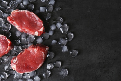 Flat lay composition with raw meat, ice cubes and space for text on dark background