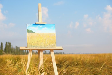 Photo of Wooden easel with beautiful picture in field. Space for text