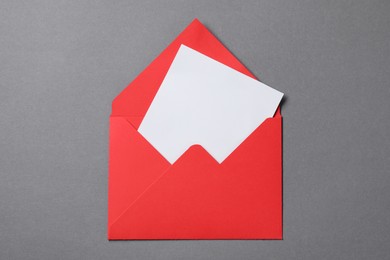 Photo of Blank sheet of paper in open letter envelope on grey background, top view