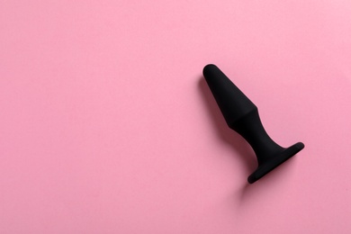 Photo of Black anal plug on pink background, top view with space for text. Sex toy