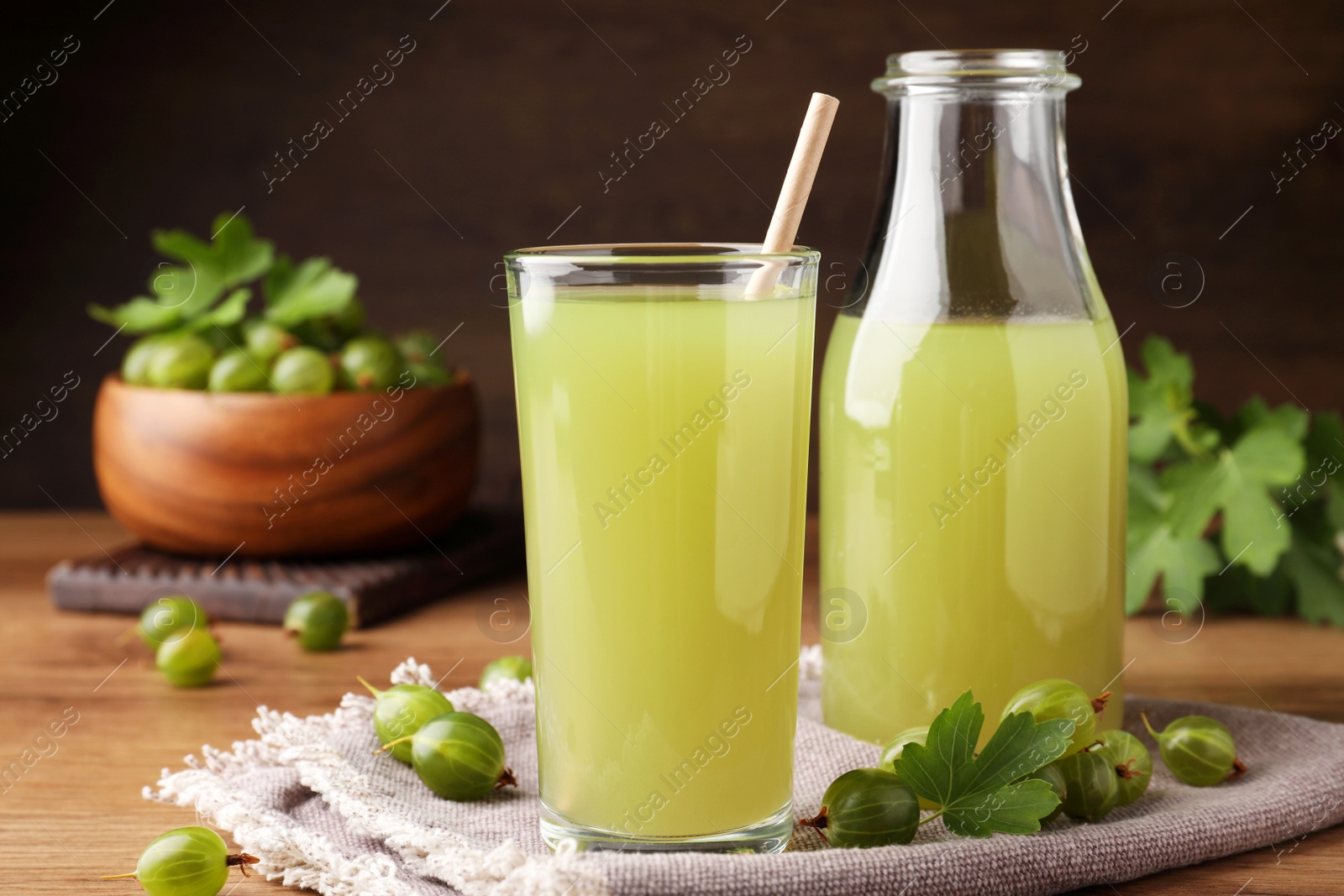 Photo of Tasty gooseberry juice on wooden table, closeup