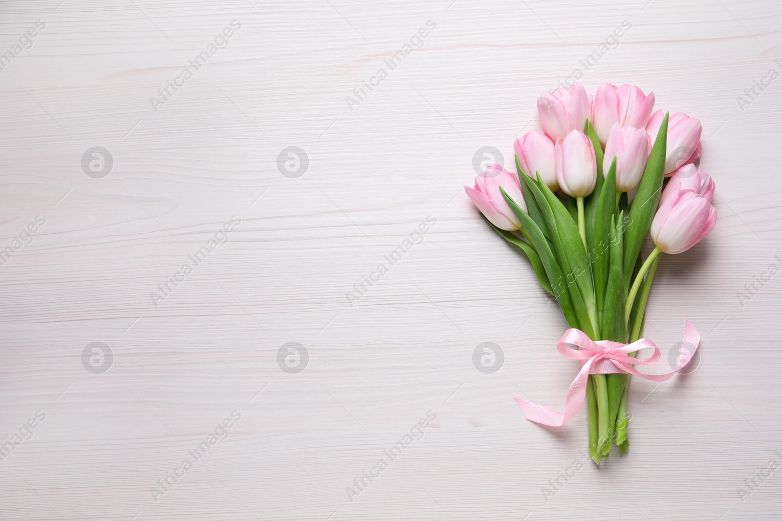 Photo of Beautiful pink spring tulips on white wooden background, top view. Space for text