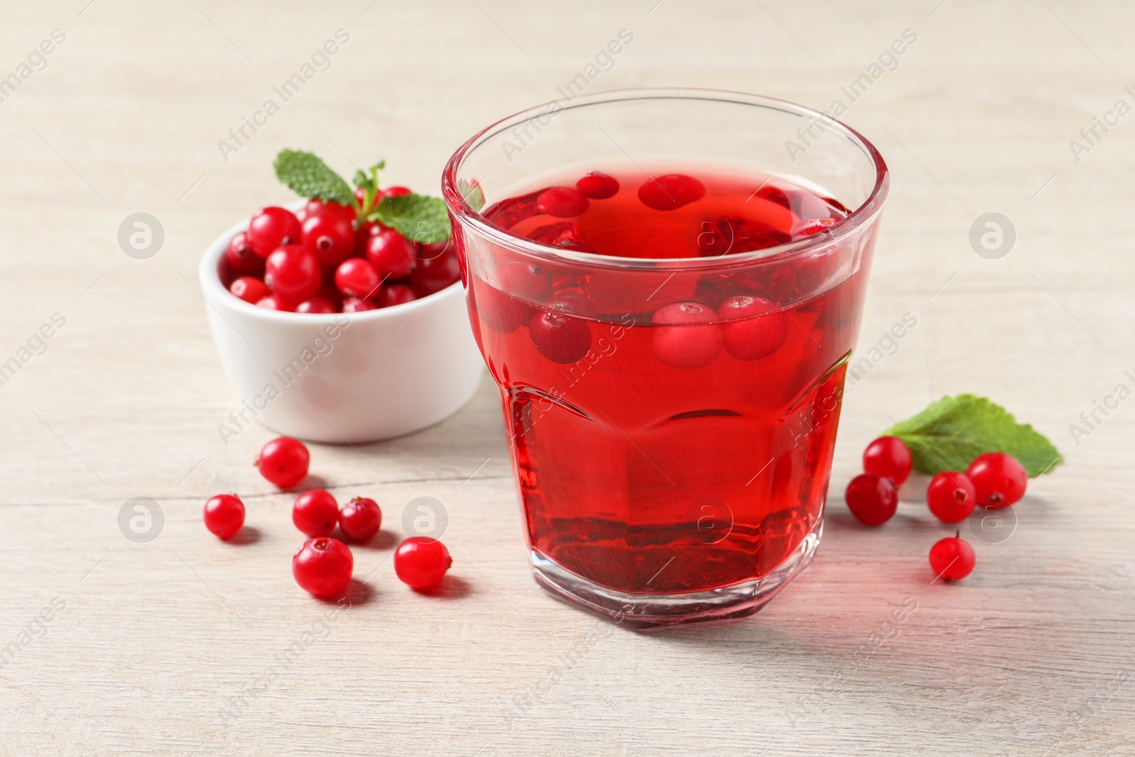 Photo of Tasty refreshing cranberry juice, mint and fresh berries on light wooden table