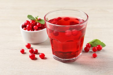 Photo of Tasty refreshing cranberry juice, mint and fresh berries on light wooden table