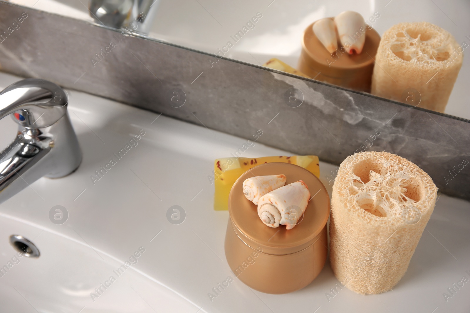 Photo of Loofah sponge and cosmetic products on sink in bathroom, space for text