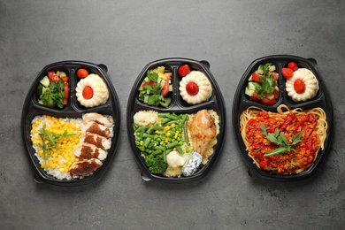 Lunchboxes with different meals on grey table, flat lay. Healthy food delivery