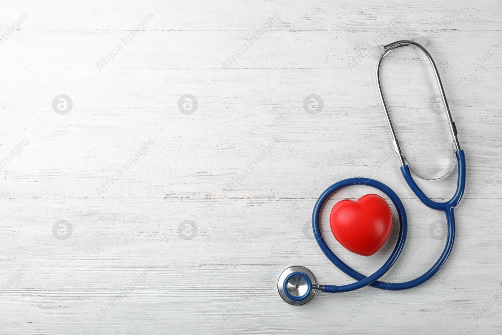 Photo of Stethoscope for checking pulse and red heart on light background, top view. Space for text