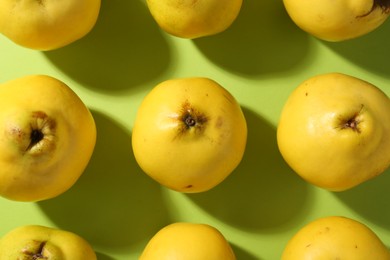 Tasty ripe quinces on light green background, flat lay