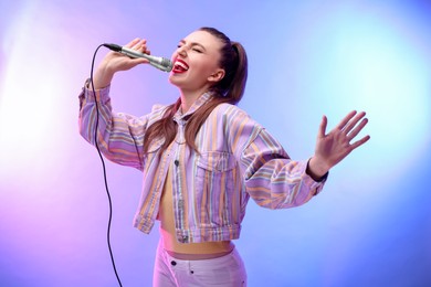 Emotional woman with microphone singing in color lights