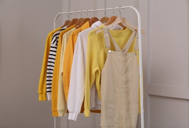 Rack with stylish women's clothes near light wall