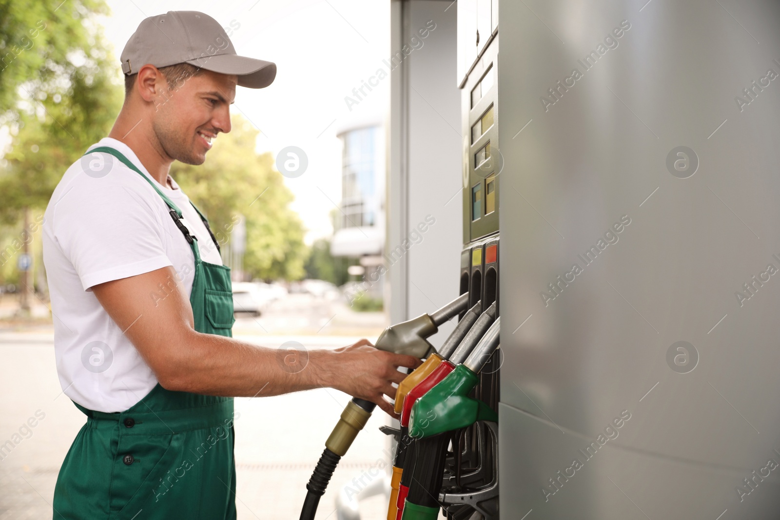 Photo of Worker taking fuel pump nozzle at modern gas station