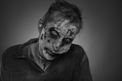 Photo of Scary zombie on dark background, black and white effect. Halloween monster
