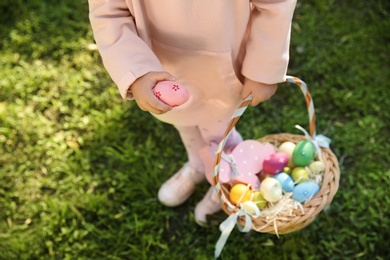 Little girl with basket of Easter eggs in park, closeup