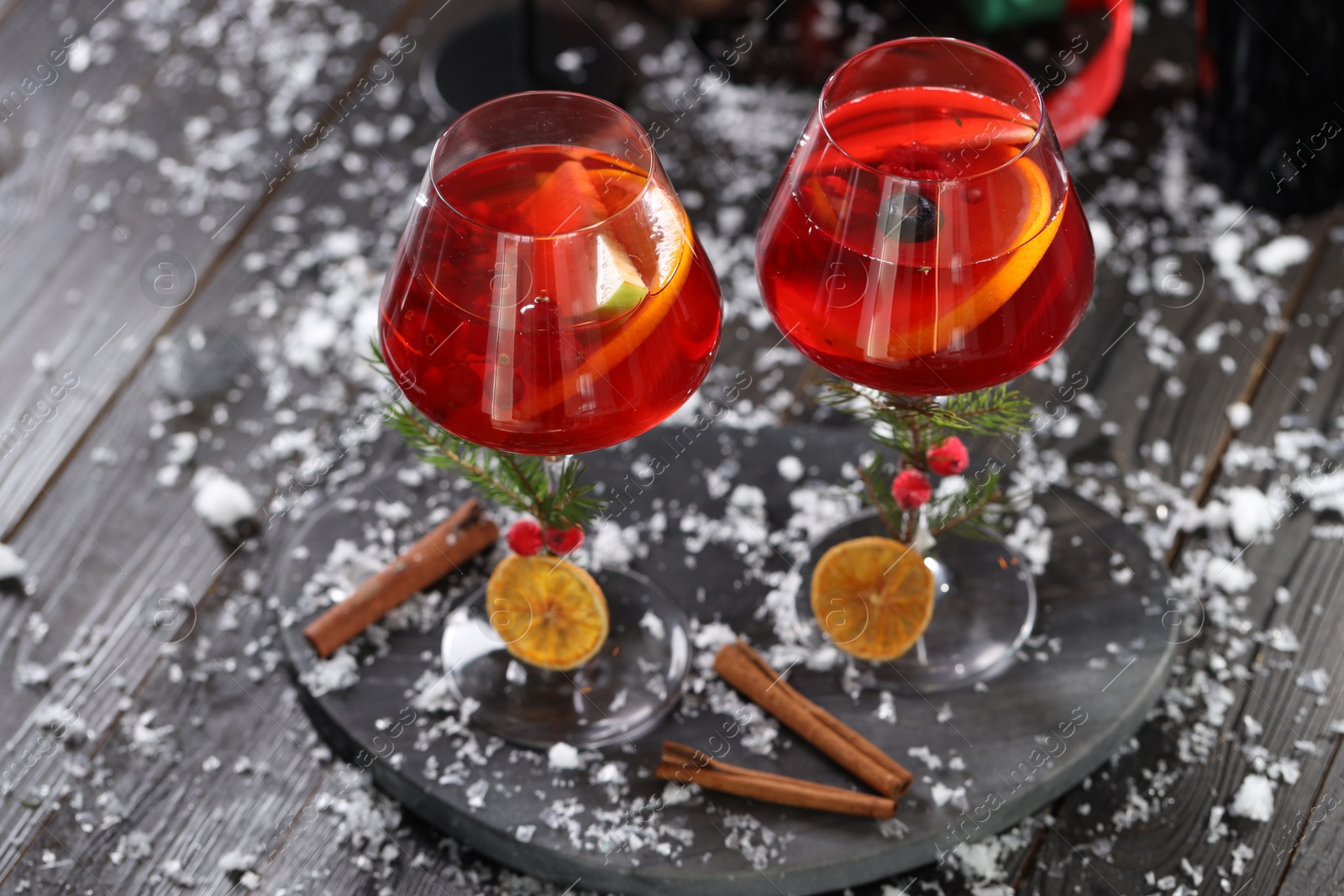 Photo of Christmas Sangria cocktail in glasses and snow on dark wooden table
