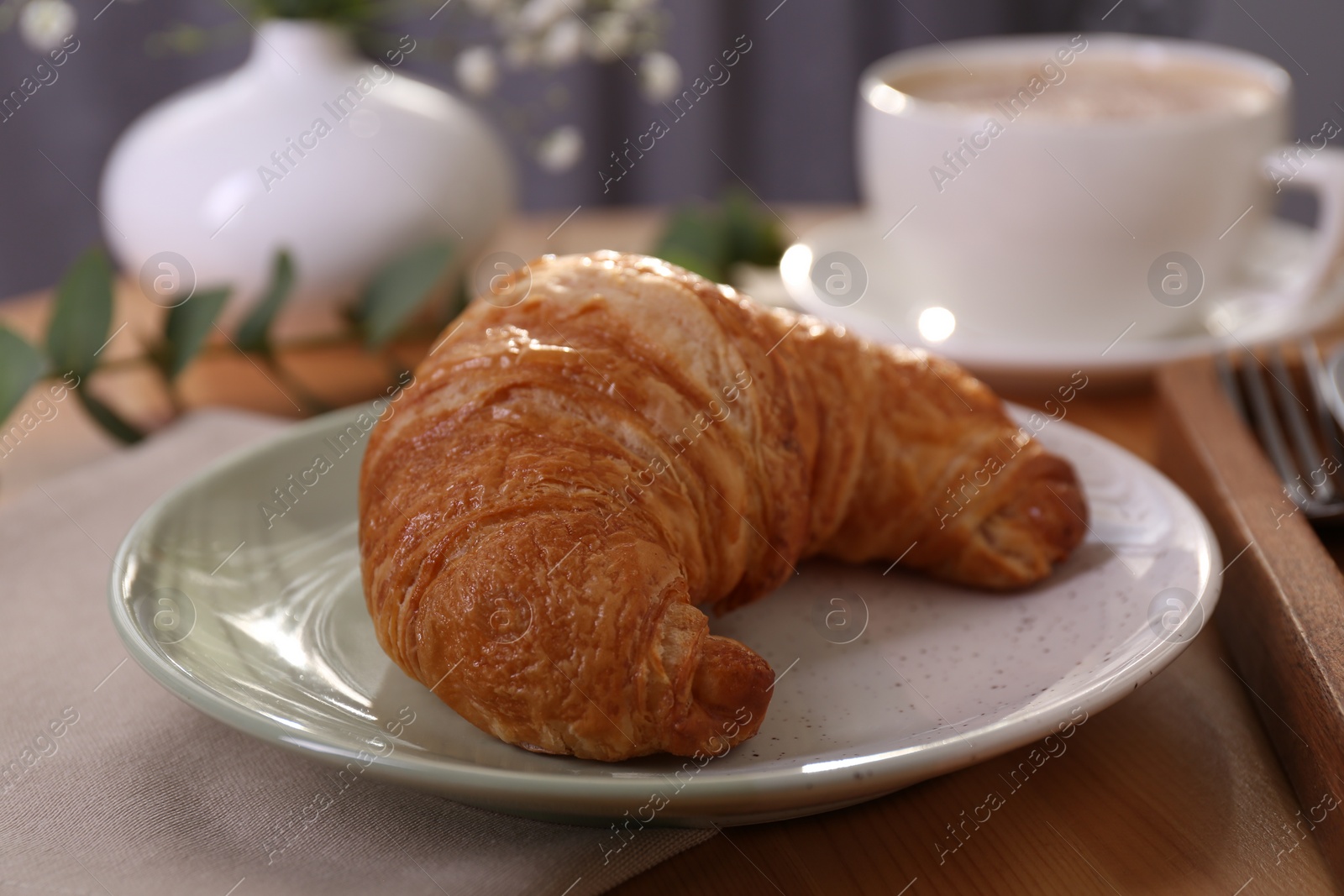 Photo of Tasty croissant served on wooden table, closeup