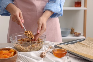 Woman making granola at table in kitchen, closeup