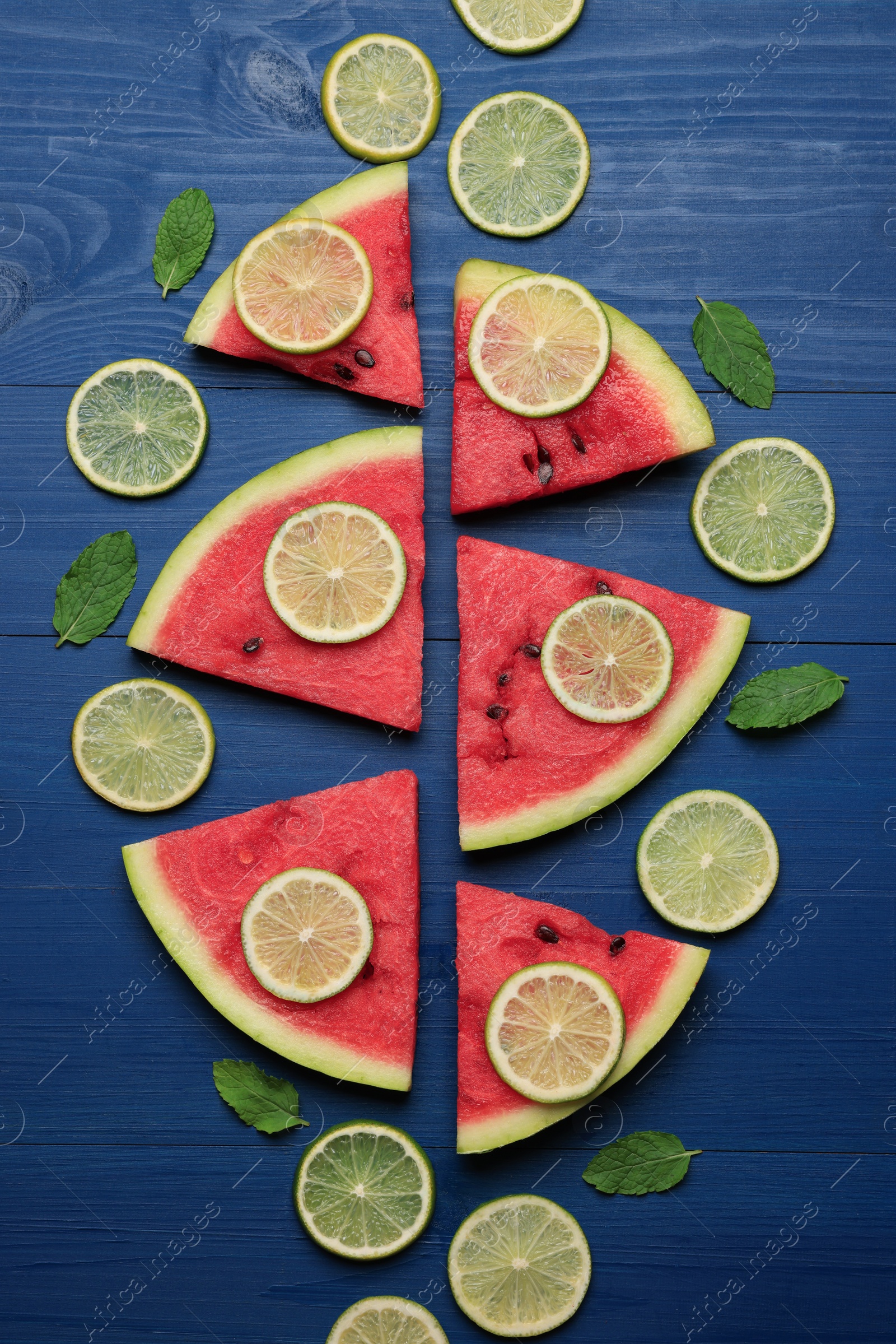 Photo of Tasty sliced watermelon and lime on blue wooden table, flat lay