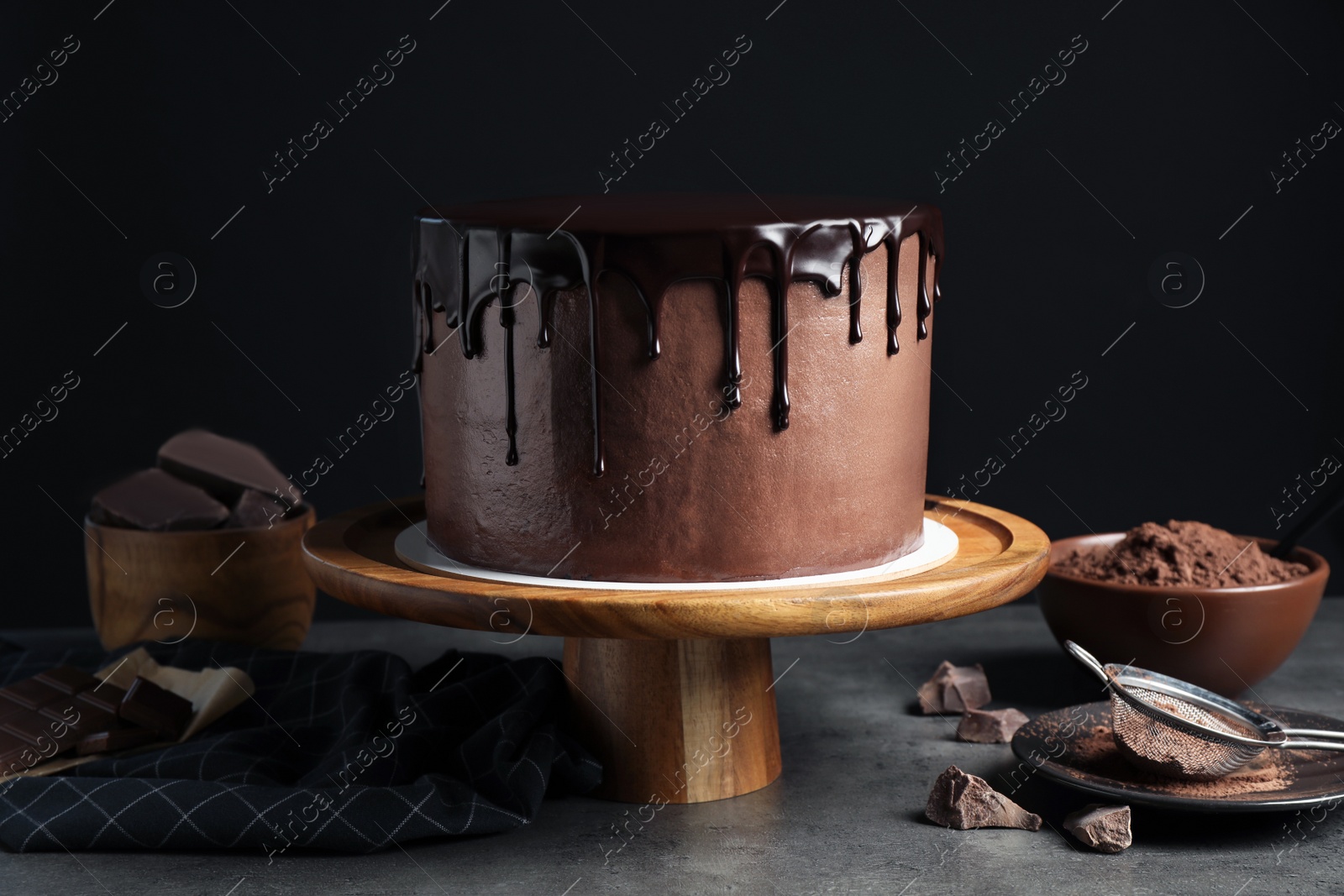 Photo of Freshly made delicious chocolate cake on grey table against black background