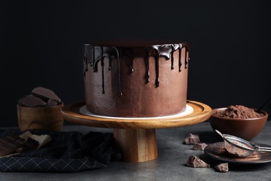 Photo of Freshly made delicious chocolate cake on grey table against black background