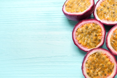 Photo of Halves of passion fruits (maracuyas) on light blue wooden table, flat lay. Space for text