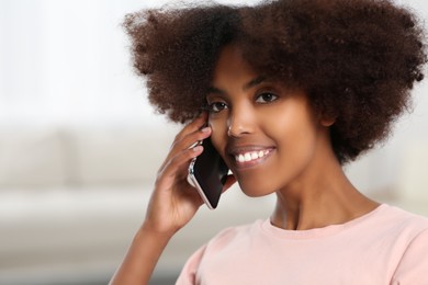 Photo of Smiling African American woman talking on smartphone at home. Space for text