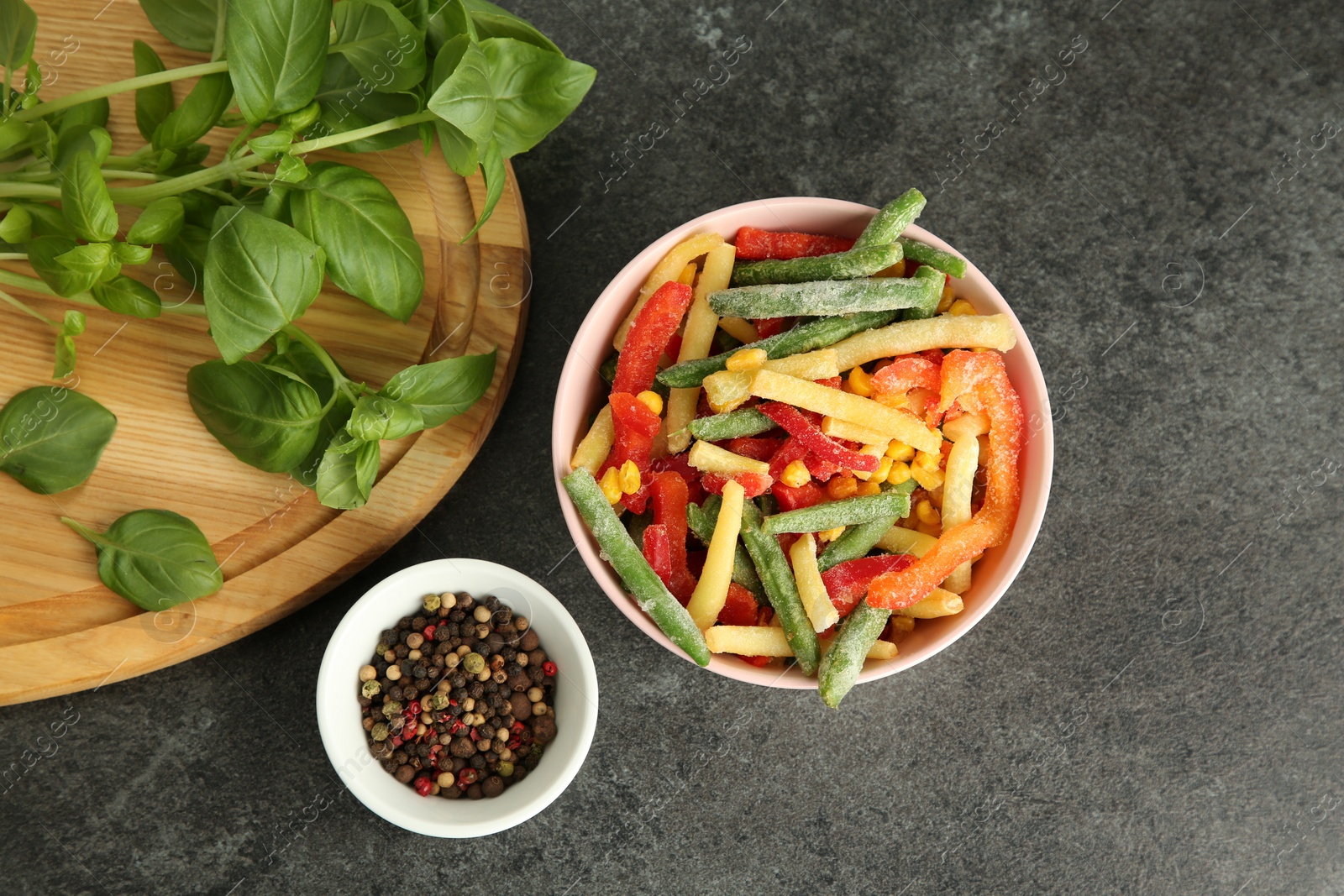 Photo of Different frozen vegetables, spices and fresh basil on grey table, flat lay